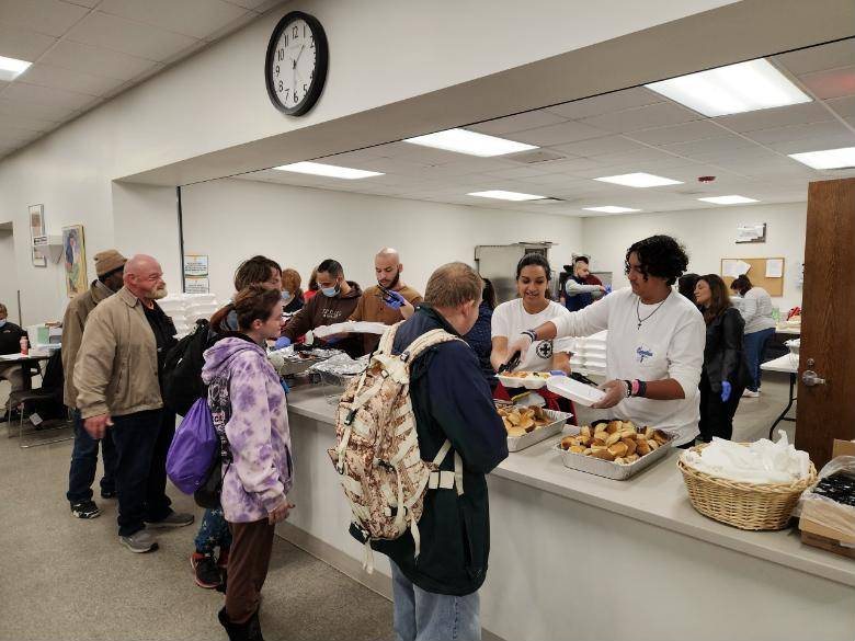 Volunteers serving meals to guests in a church hall